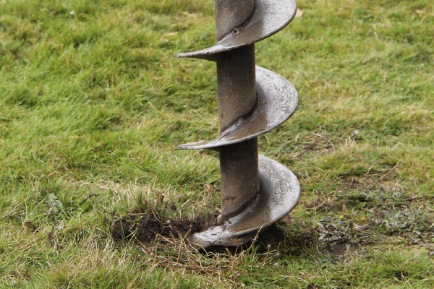 A post-hole digger boring the drain hole for a window well