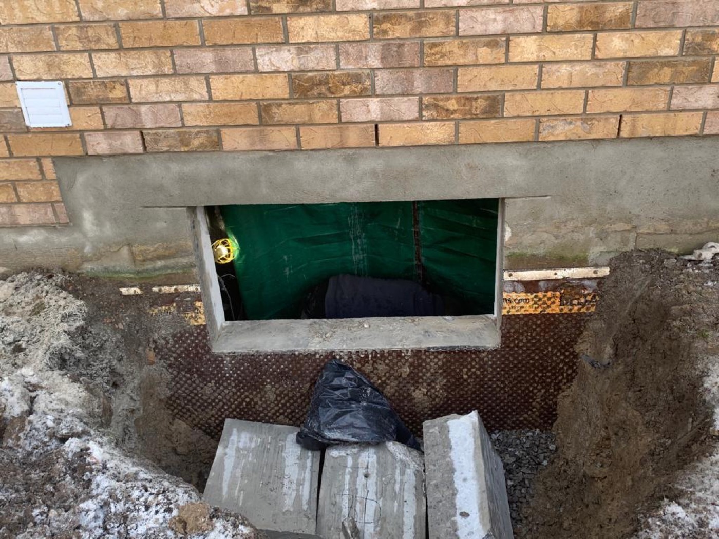 An excavated window well against a foundation wall, before the window is set